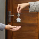 Remise des clés d'un logement devant la porte d'entrée, entre propriétaire et locataire